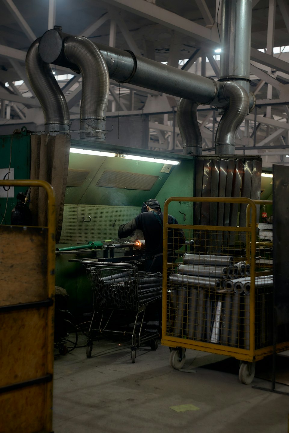 Pracownik w kasku szlifuje metal w fabryce.